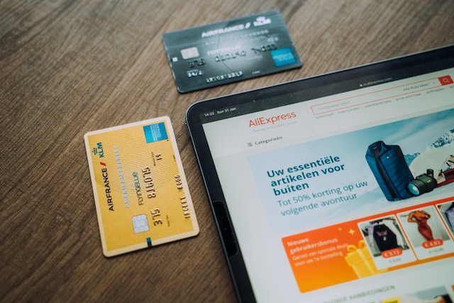 Karta kredytowa leży obok tabletu na któym jest otworzona strona Aliexpress