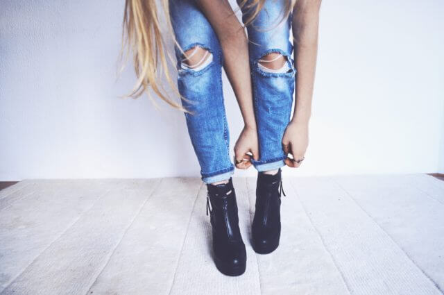 Kobieta w dziurawych jeansach ubiera modne buty